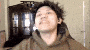 a man wearing a hoodie is making a funny face in front of a door .