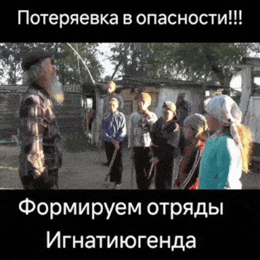 a man with a beard stands in front of a group of people with foreign writing on the bottom