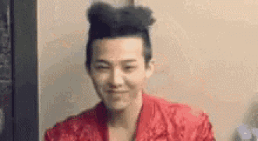 a man with a bun on his head is smiling and wearing a red shirt .