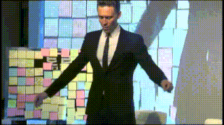 a man in a suit and tie stands in front of a wall of post it notes