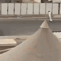 a white car is driving down a street next to a cone shaped structure .