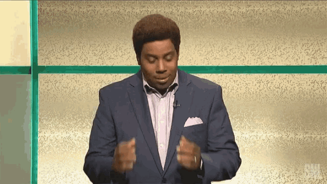 a man in a suit and tie is standing in front of a screen that says snl on it