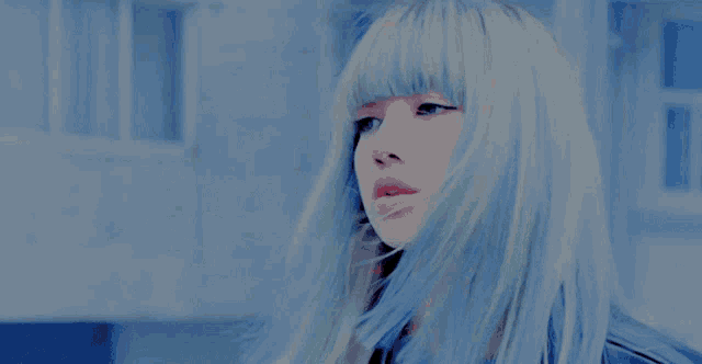 a woman with blue hair and bangs looks down