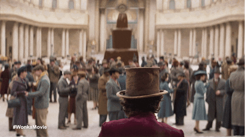 a man in a top hat stands in front of a crowd of people with the words wonka movie written on the bottom