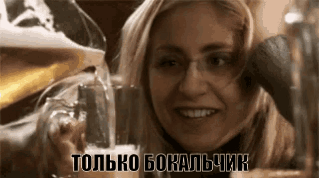 a woman with glasses is smiling while a glass of beer is being poured into her