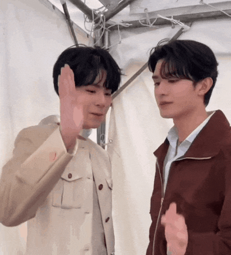 two young men are standing next to each other and giving each other a high five