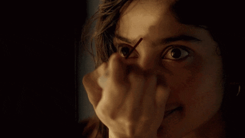a close up of a woman 's face with a stick in her eye