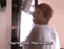 a woman is standing in front of a microwave saying `` they 're done , they 're done ! ''