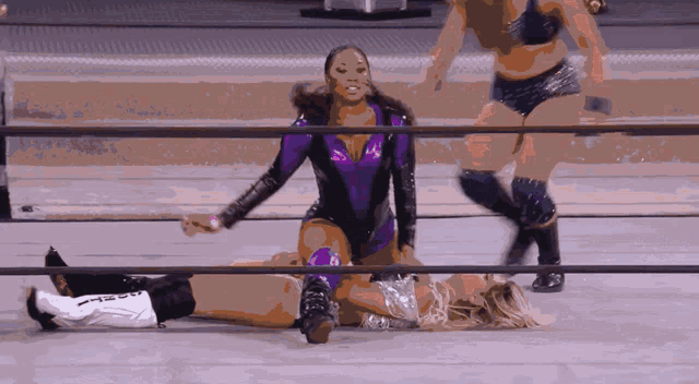 a woman in a purple outfit is kneeling over another woman who is laying on the floor