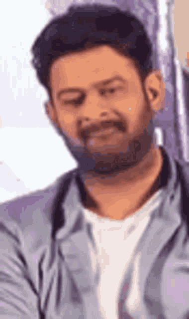 a close up of a man with a beard wearing a white shirt and a blue jacket .