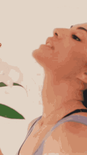 a close up of a woman 's face with a flower in her hand