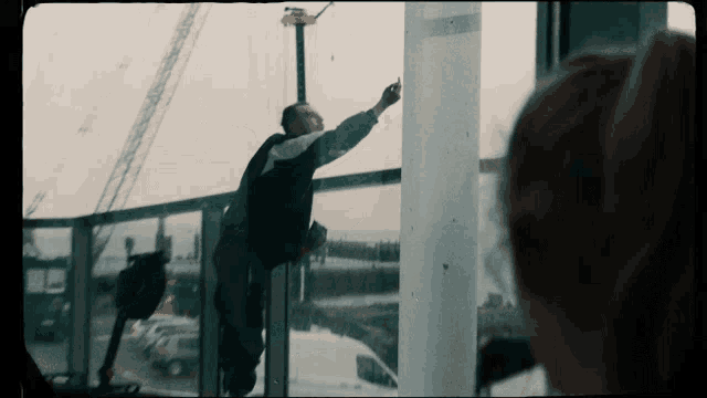 a man is standing on a balcony painting a pole