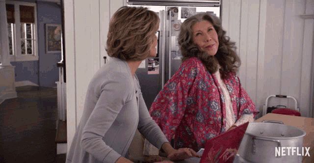 two women standing in a kitchen with a netflix logo on the bottom right