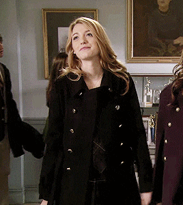 a woman in a black coat is standing in a room