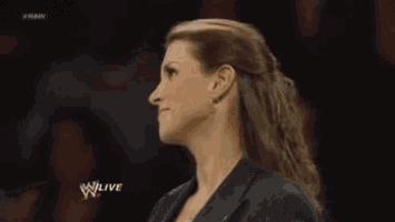 a woman is standing in a wrestling ring wearing a suit and smiling .