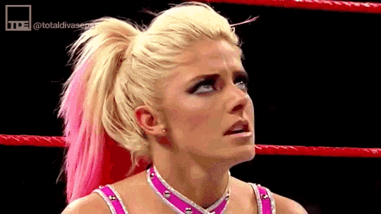 a woman with blonde hair and pink highlights is standing in a wrestling ring and making a funny face .