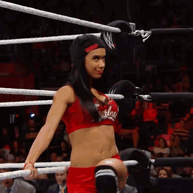 a woman in a red top that says fearless on it is in a wrestling ring