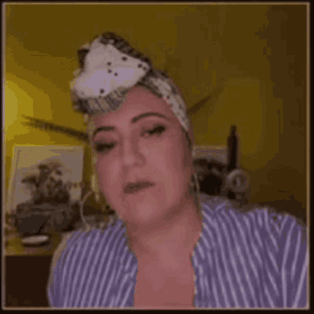 a woman wearing a headband and a striped shirt is making a face .