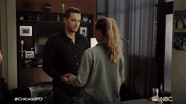 a man and a woman are shaking hands in a living room with #chicagopd on the bottom