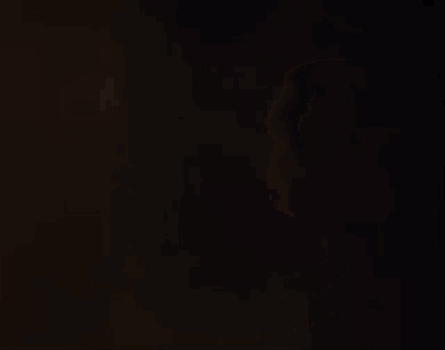 a man sits in front of a lamp in a dark room .