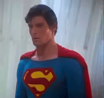 a man in a superman costume is standing in front of a window