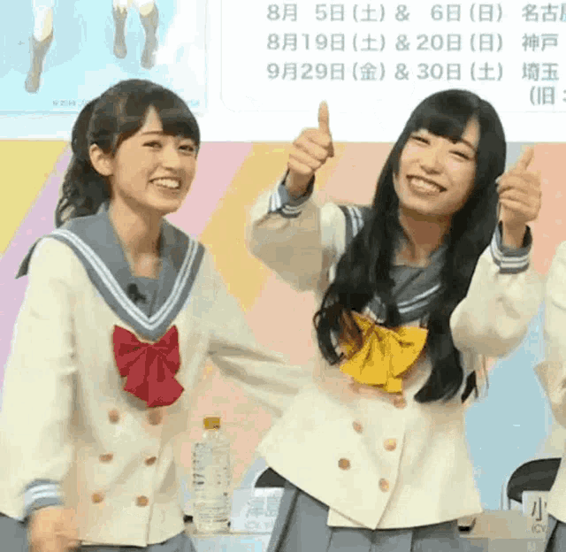 two girls are giving each other a thumbs up and smiling