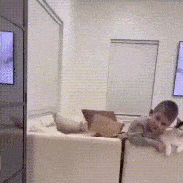 a young boy is laying on a couch in a living room with a tv behind him .