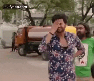 a man is covering his face with his hand in front of a truck .