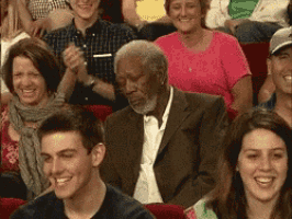 a man in a suit sits in a crowd of people applauding
