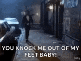 a man in a tuxedo is walking down a sidewalk with the words `` you knock me out of my feet baby ! ''