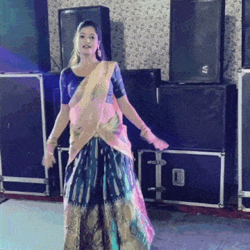 a woman in a saree is dancing in front of a v7 speaker