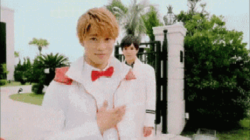 a man in a white jacket and red bow tie is standing next to another man in a white jacket and red bow tie .