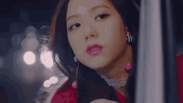 a close up of a woman wearing a red dress and pink earrings .