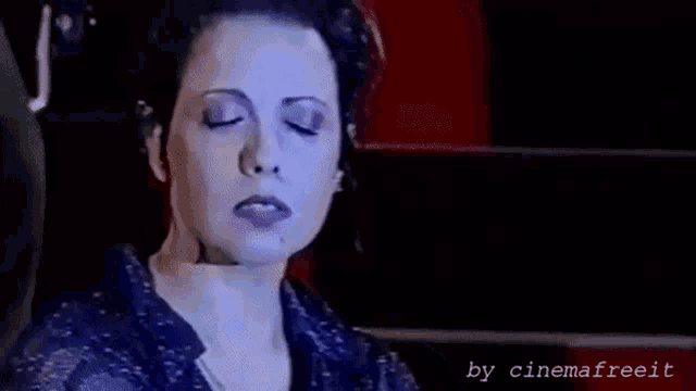 a woman is sitting in a dark room with her eyes closed and her mouth open .
