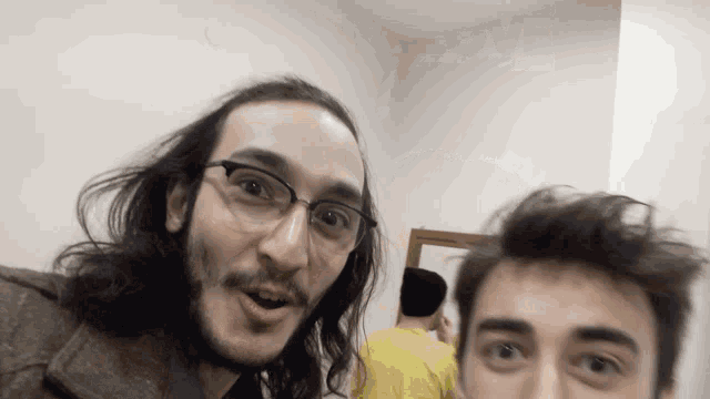a man with long hair and glasses takes a selfie
