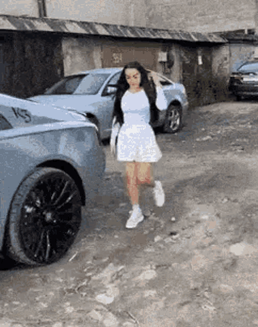 a woman in a white dress is running towards a car .