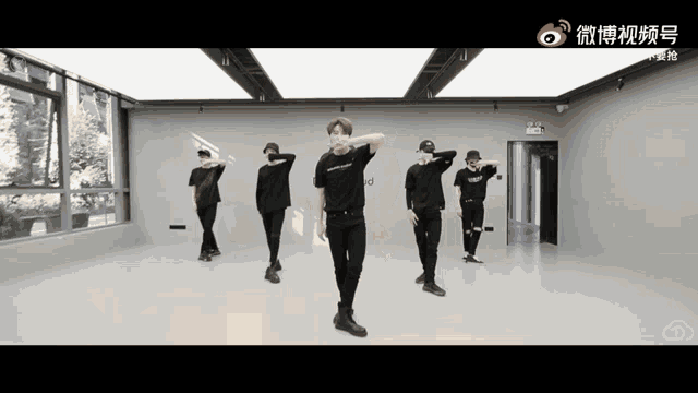 a group of young men are dancing in a room with chinese writing