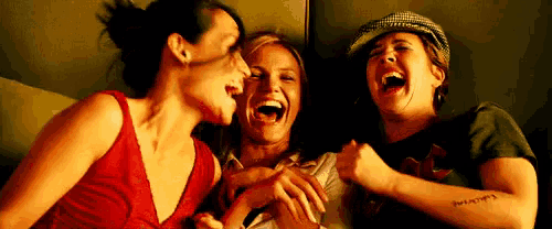 three women are laughing together while one has a tattoo on her arm