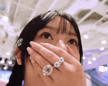 a woman with a ring on her finger is covering her mouth with her hand