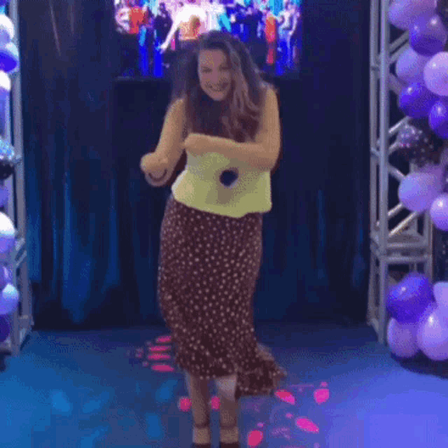 a woman in a polka dot skirt is holding a microphone and dancing