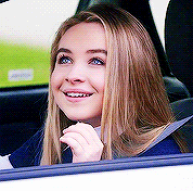 a woman is sitting in the back seat of a car smiling .