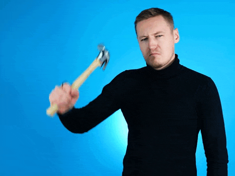 a man in a black sweater is holding a hammer in his right hand
