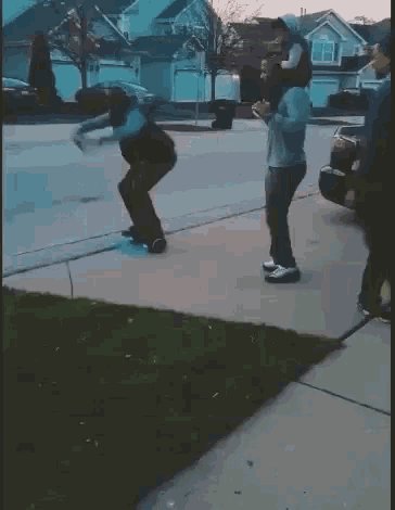 a man is carrying a child on his shoulders on a sidewalk while another man watches .