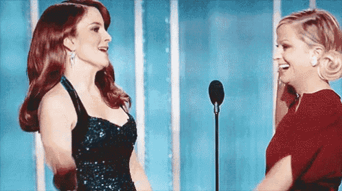 two women are standing next to each other in front of a microphone and smiling