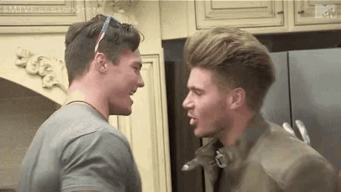 two young men are standing next to each other in a kitchen .