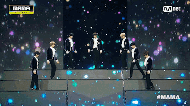 a group of young men are dancing on a stage with a mnet logo in the background