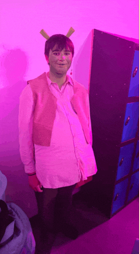 a man in shrek costume is standing in front of a purple wall