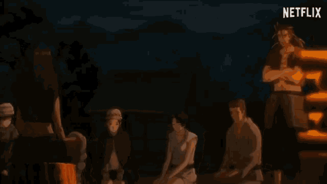 a group of people are gathered around a fire with a netflix logo in the background