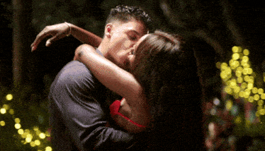 a man and a woman are kissing in front of lights