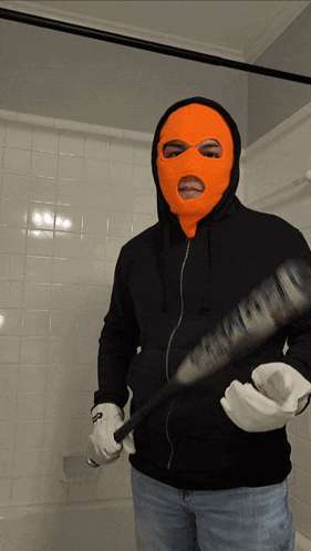a man in an orange ski mask is holding a bat